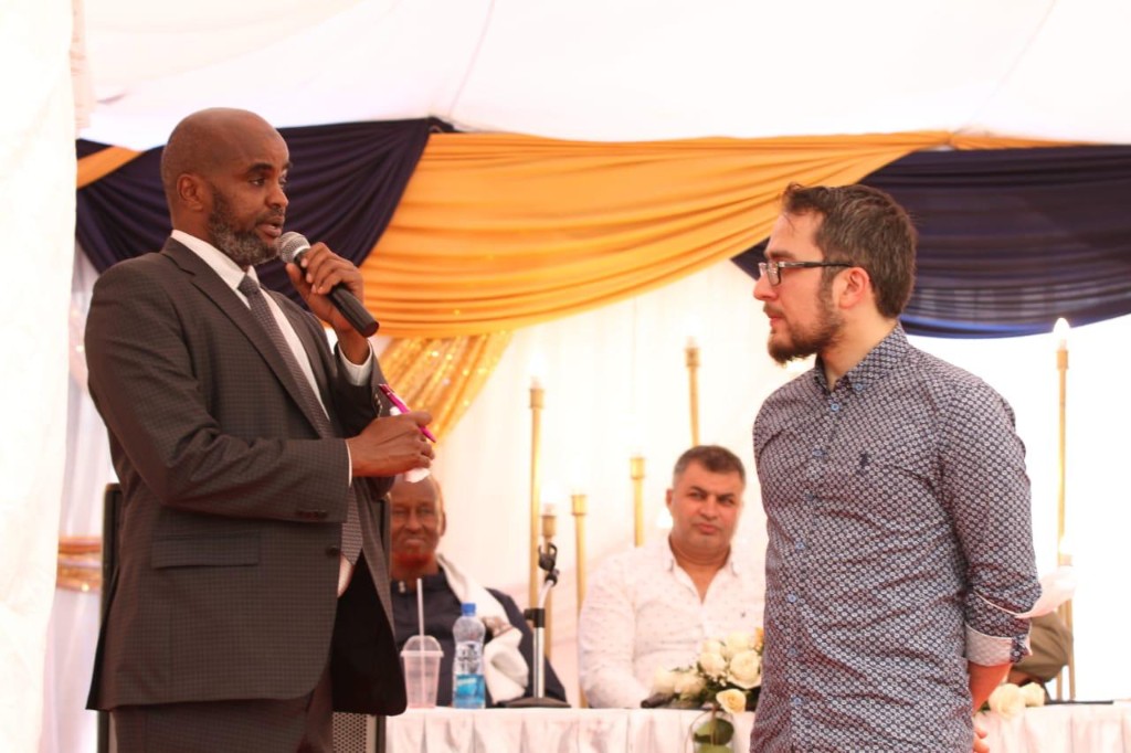 Abdi Ahmed speaking with a guest under a decorated marquee