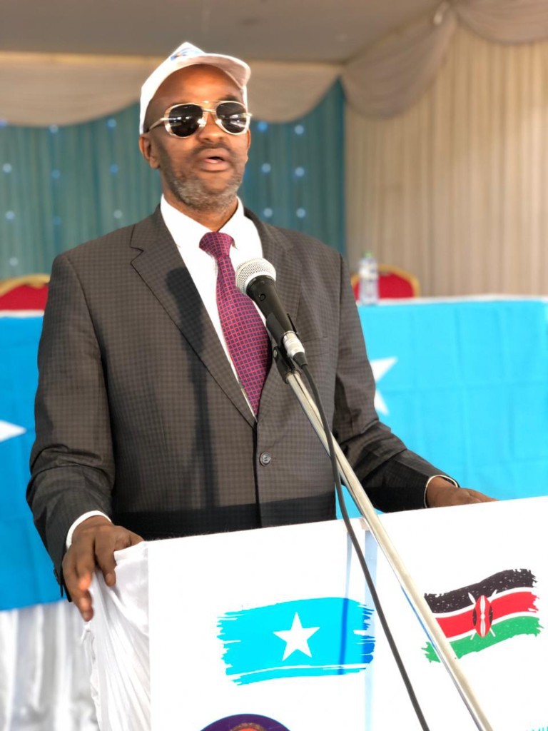 Abdi Ahmed speaking at a podium marked with Kenyan and Somali flags
