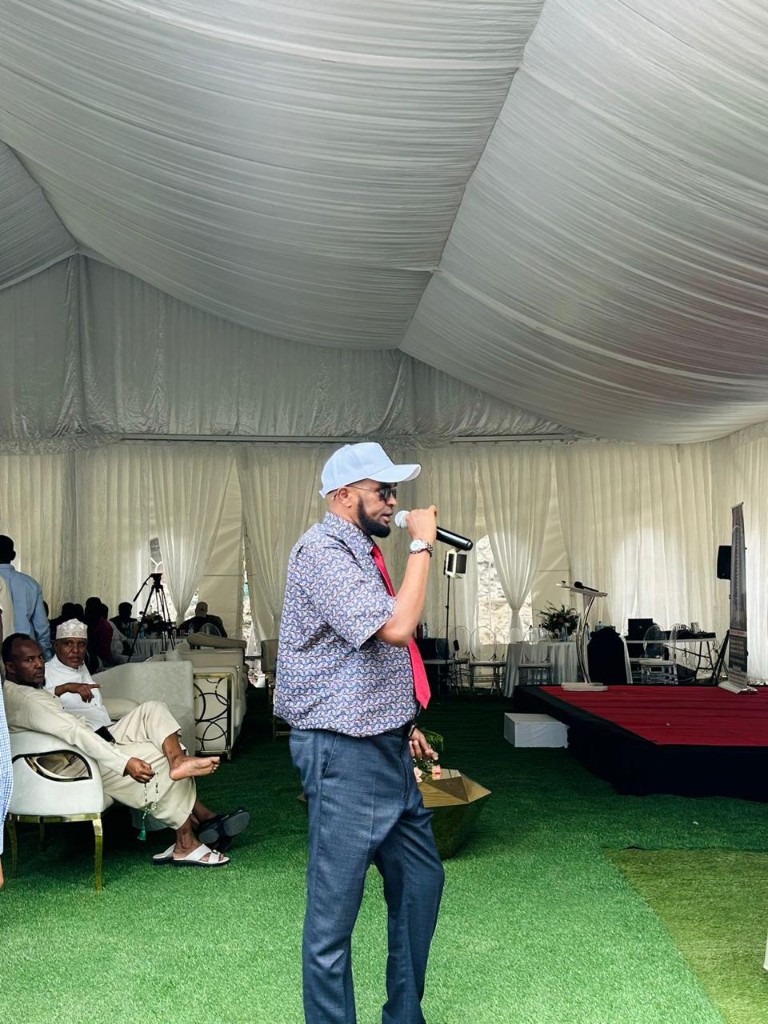 Abdi Ahmed hosting an audience inside a white marquee on green turf